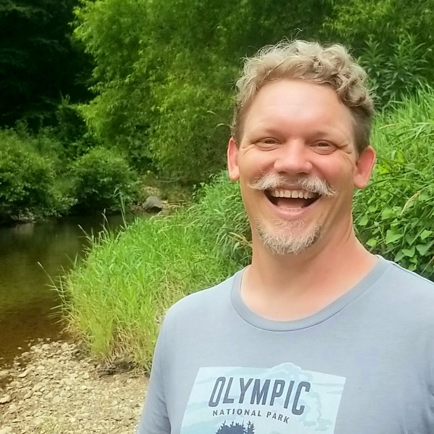 Paul Motten outdoors beside a creek